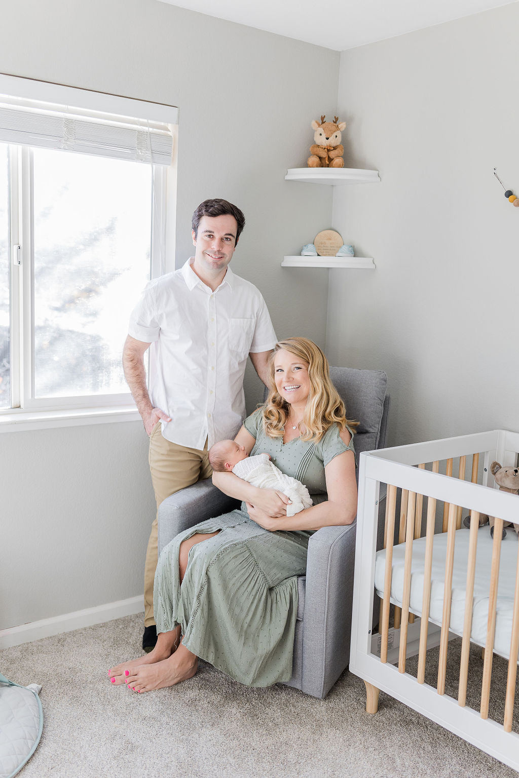 mom holding newborn baby with dad standing next to her in the nursery