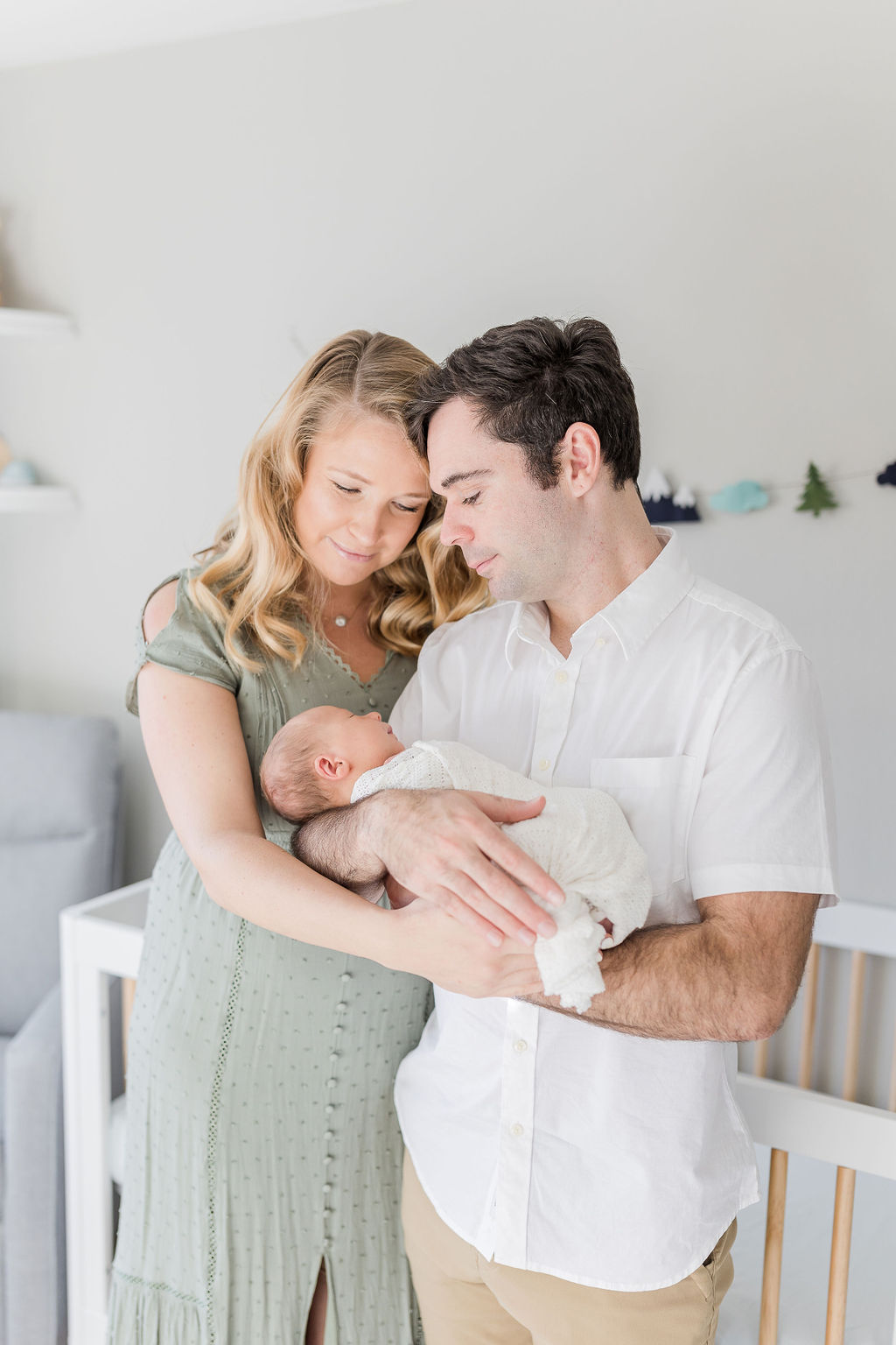 new mom and dad holding their newborn in his nursery baby connection roseville