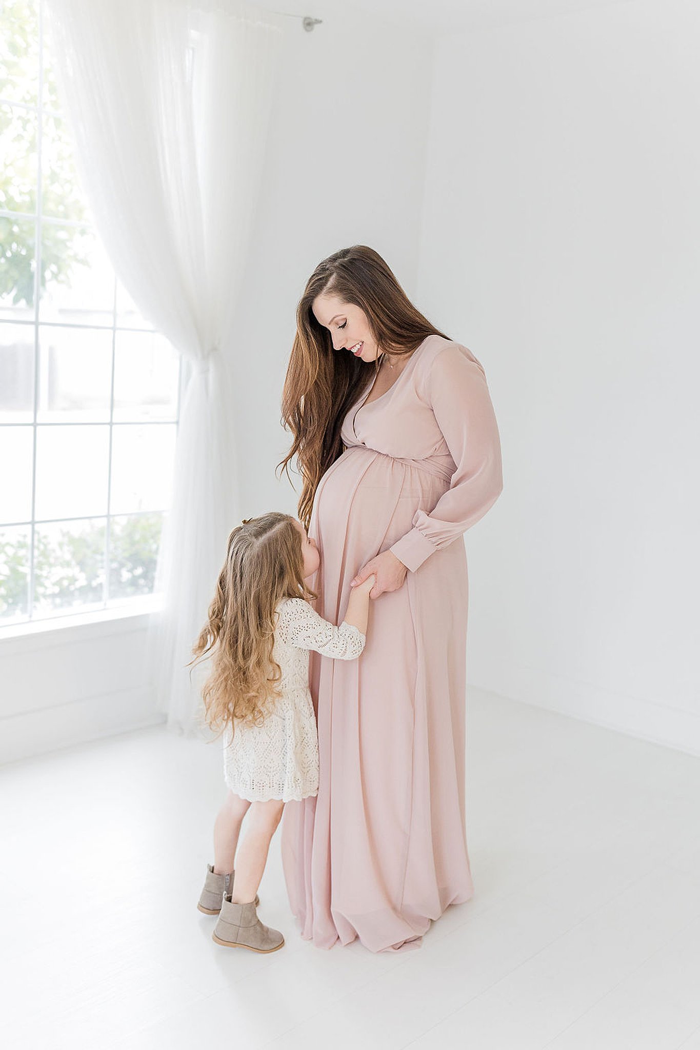 mom to be in blush gown with her daughter kissing her bump Birth Center Sacramento
