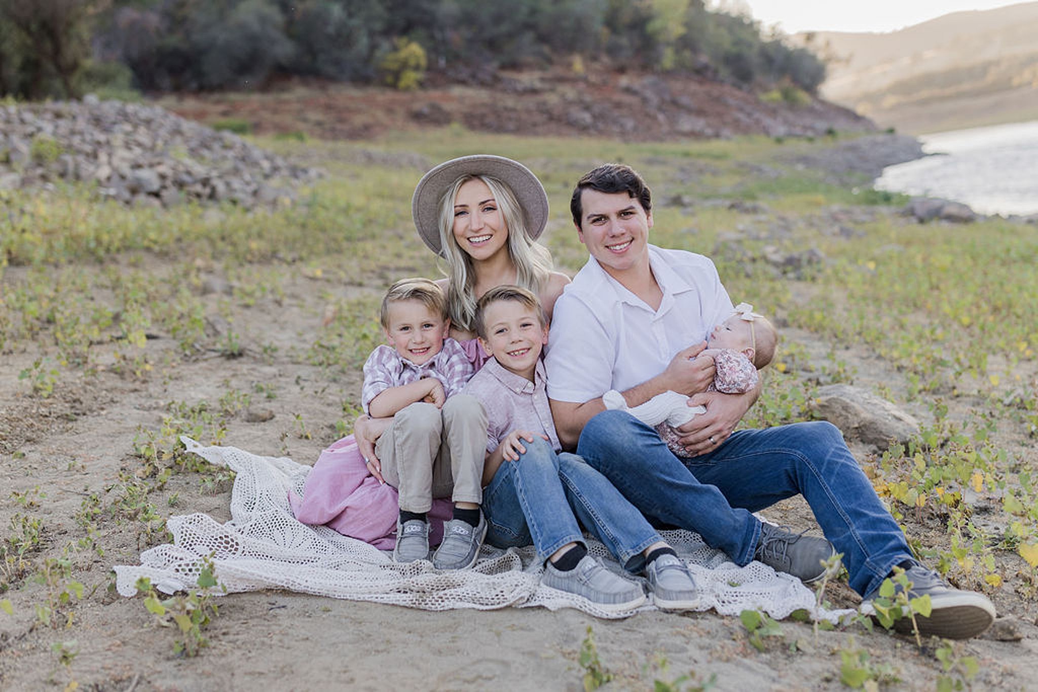family of 5 sitting together on a blanket in a field Just Between Friends Folsom